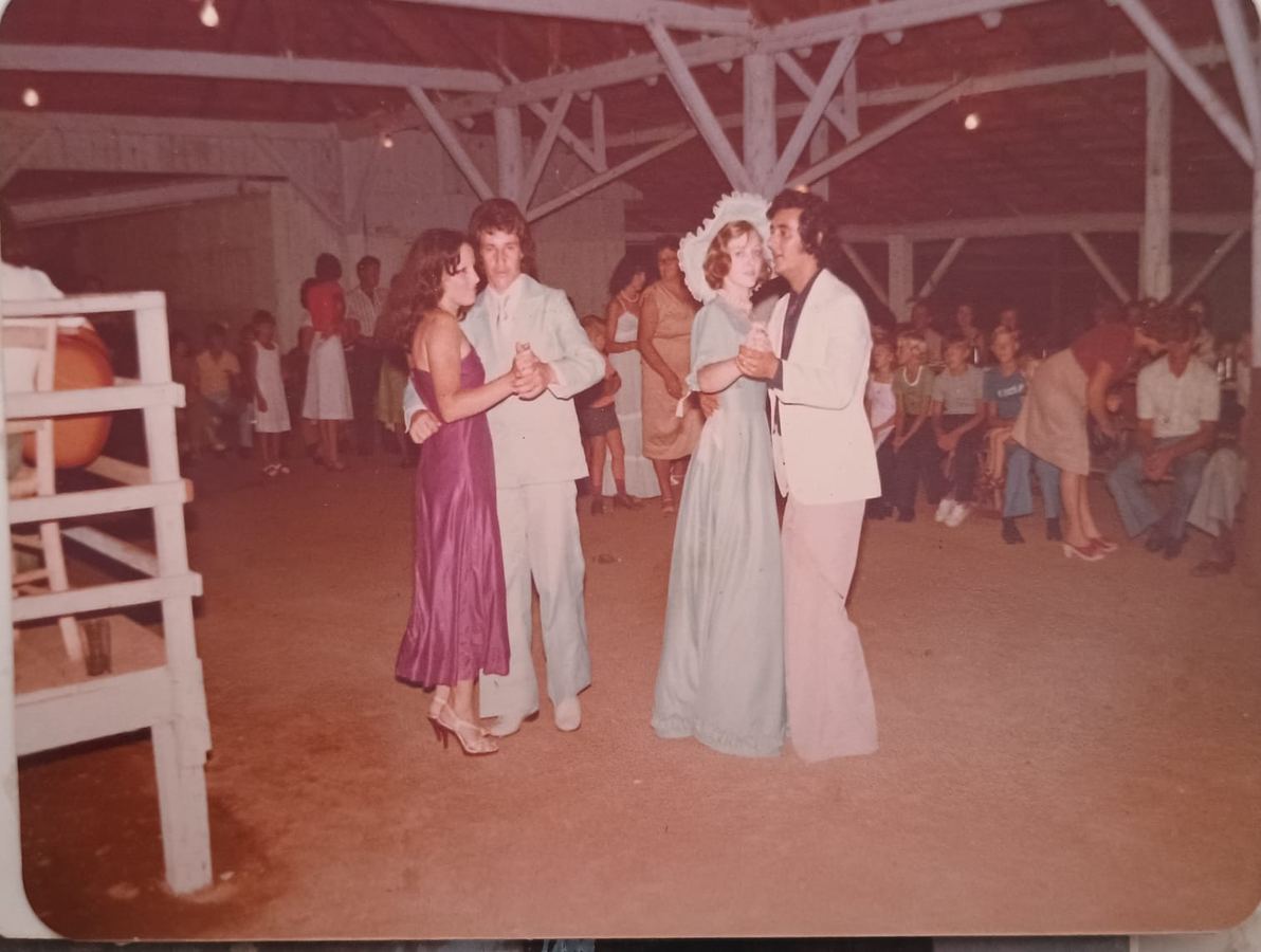Fotografia antiga de uma festa com casais dançando ao fundo