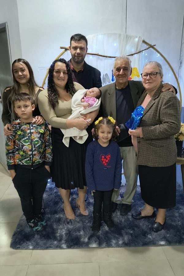 Família reunida em uma sala, com bebê e crianças