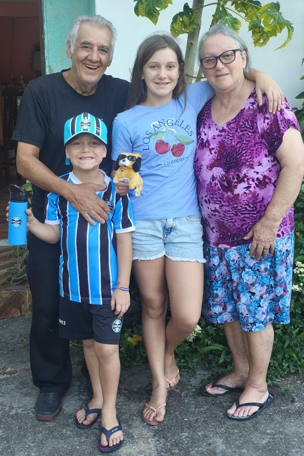 Um senhor com os netos e uma mulher, abraçados