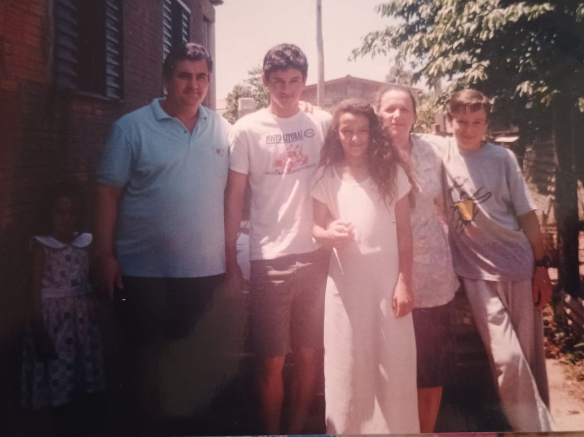 Fotografia de família diante de uma casa de tijolos