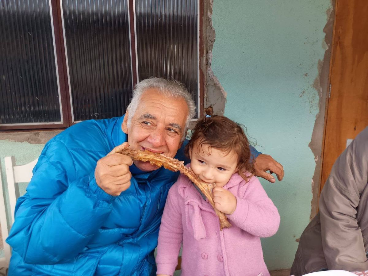 Um senhor sorrindo, dividindo um doce com uma menina