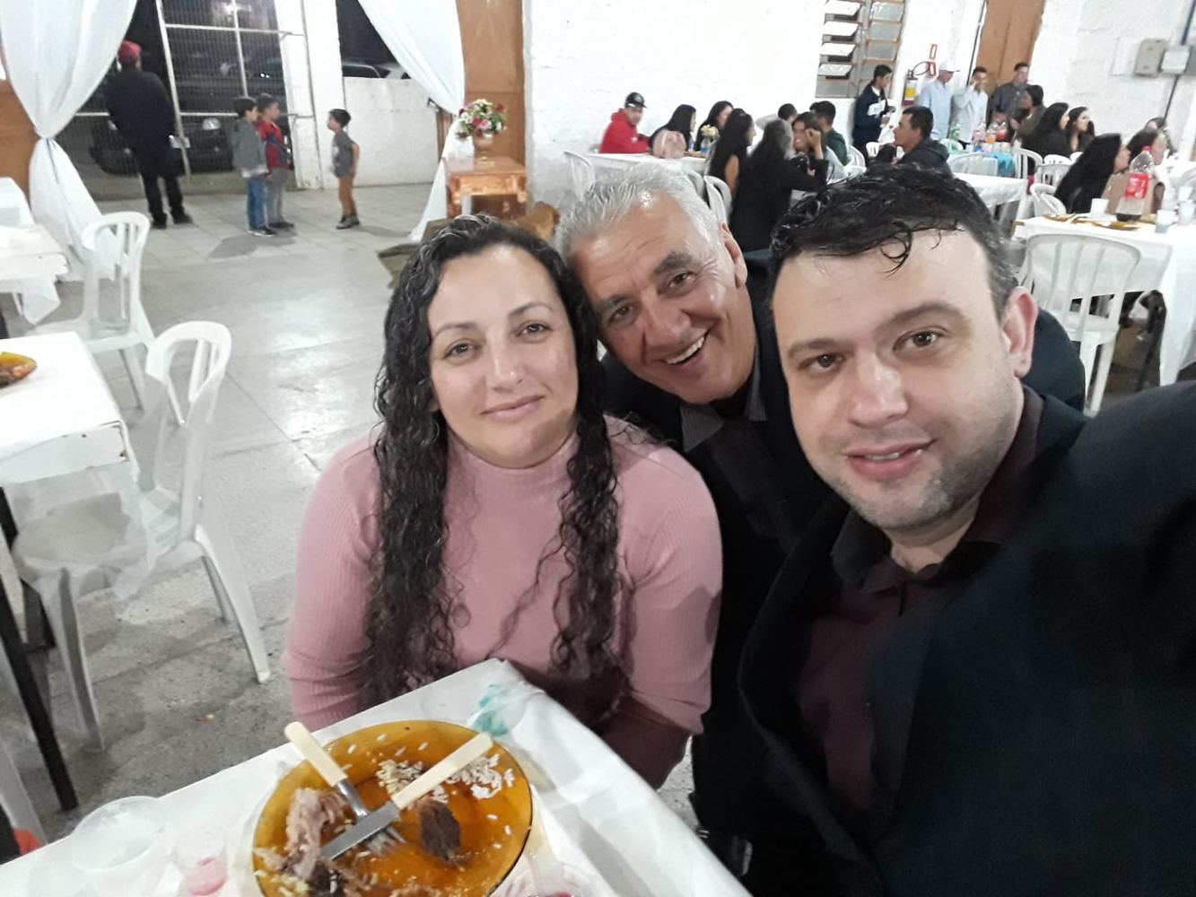 Selfie de Sinval entre uma mulher e um homem numa festa