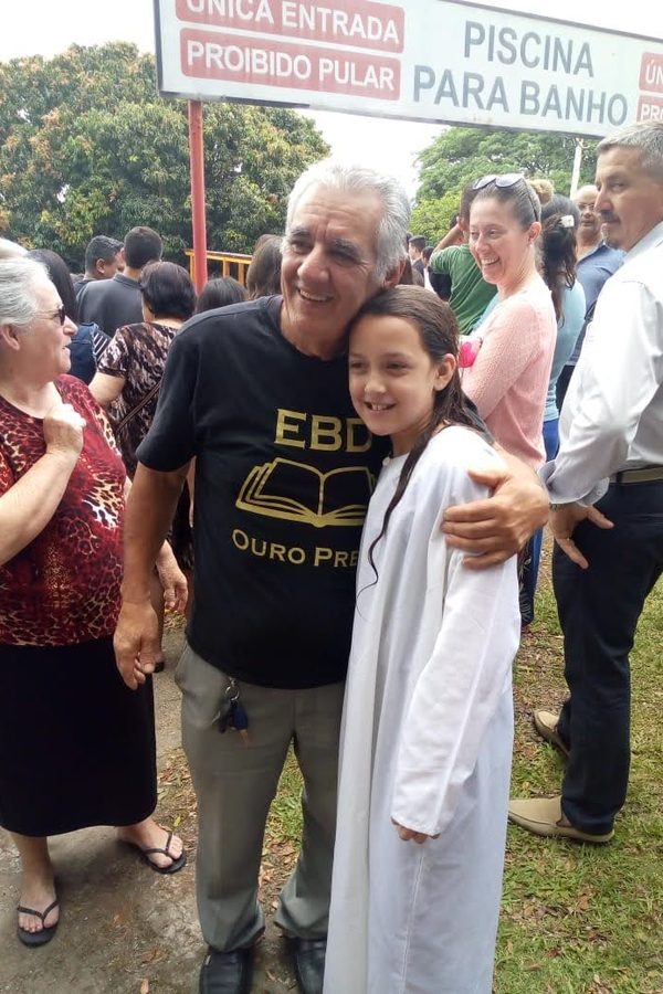 Sinval em um encontro da igreja, ao lado de uma menina de roupa branca