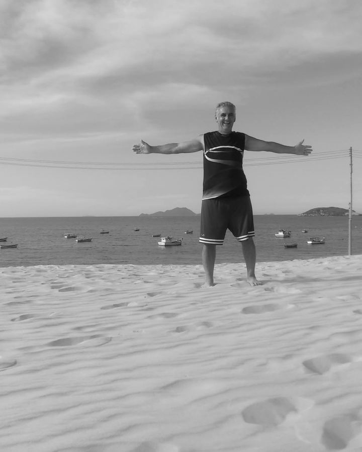 Sinval de braços abertos numa praia de dunas